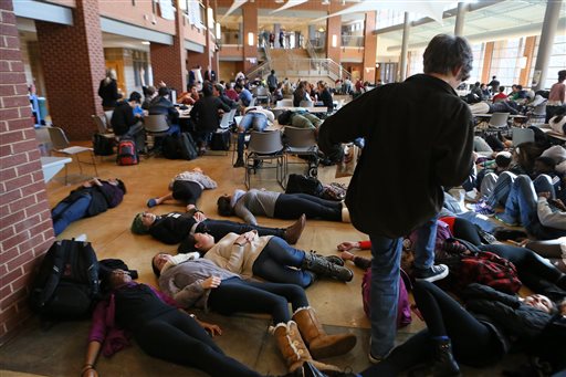 In this Dec. 1, 2014 file photo, students participating in a die lie on the cafeteria floor at Clayton, Mo., High School following a grand jury's decision not to indict a white police officer who killed 18-year-old black Michael Brown. The American Civil Liberties Union filed the lawsuit Monday, Jan. 5, 2015 on behalf of a jury member asking a Missouri court to remove a lifetime order that prevents jurors from discussing the case.  (AP Photo/St. Louis Post-Dispatch,  Cristina Fletes-Boutte, File)