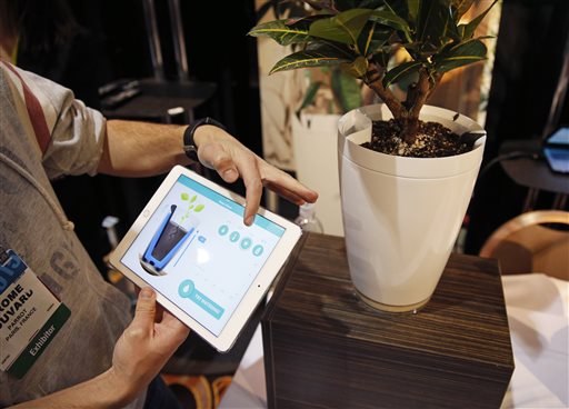 Jerome Bouvard demonstrates the Parrot Pot at CES Unveiled, a media preview event for CES International, Sunday, Jan. 4, 2015, in Las Vegas. The pot is linked to mobile devices and will automatically water your plant. (AP Photo/John Locher)