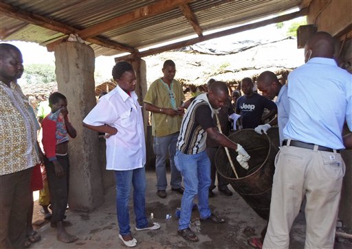 In this photo taken on Monday, Jan. 12, 2015, Mozambique government officials gather samples from a drum that was allegedly used to make local beer  that made people sick in Tete province, Mozambique.  Three more people have died from drinking contaminated beer, bringing the number of fatalities to 72, health authorities in Mozambique said on Tuesday. However, the number of victims hospitalized has decreased to 35 from 196, according Paula Bernardo, director of health, women and social welfare in the northeastern Tete province. (AP Photo/Antonio Chimundo)