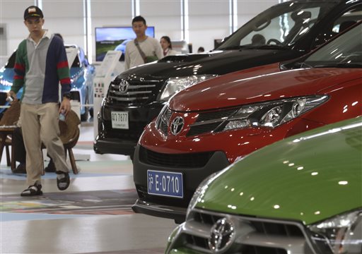 In this May 8, 2014 photo, visitors look at cars displayed at a Toyota gallery in Tokyo. Toyota Motor Corp. stayed at the top in global vehicle sales in 2014, but is pessimistic about this year. The Japanese automaker sold 10.23 million vehicles, beating out Volkswagen and General Motors to take that auto industry crown for the third year straight. Toyota was less upbeat about the future, expecting to sell fewer trucks and cars this year, at 10.15 million vehicles, down 1 percent year-on-year, according to numbers released Wednesday, Jan. 21, 2015. (AP Photo/Koji Sasahara, File)