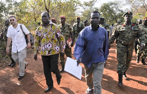 In this photo taken Friday, Jan. 16, 2015 and released by the Uganda People's Defence Force (UPDF), a man said by the UPDF to be the wanted Lord's Resistance Army (LRA) commander Dominic Ongwen, center-right, is handed over by the UPDF to the African Union Regional Task Force who later handed him over to Central African Republic authorities, in the Central African Republic. Central African Republic's Seleka rebels, who once overthrew the government, say they're entitled to a $5 million reward from the U.S. government because they say they captured and handed over the wanted international war crimes suspect Dominic Ongwen to American forces. (AP Photo/Uganda People's Defence Force, Mugisha Richard)