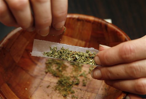 Rica Madrid poses for a photograph as she rolls a joint in her home on the first day of legal possession of marijuana for recreational purposes, Thursday, Feb. 26, 2015, in Washington. Democratic Mayor Muriel Bowser defied threats from Congress by implementing a voter-approved initiative on Thursday, making the city the only place east of the Mississippi River where people can legally grow and share marijuana in private. (AP Photo/Alex Brandon)