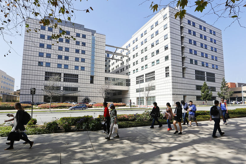 People walk near the Ronald Reagan UCLA Medical Center in Los Angeles building in Los Angeles, Thursday, Feb. 19, 2015. A "superbug" outbreak suspected in the deaths of two patients at UCLA Medical Center in Los Angeles has raised questions about the adequacy of the procedures for disinfecting a medical instrument used on more than a half-million people in the U.S. every year. (AP Photo/Damian Dovarganes)