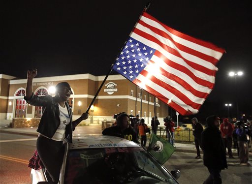 Gina Gowdy joins protesters on the street outside a Ferguson, Mo., fire station, Wednesday, March 4, 2015, in Ferguson. The Justice Department on Wednesday cleared a white former Ferguson police officer in the fatal shooting of an unarmed black 18-year-old, but also issued a scathing report calling for sweeping changes in city law enforcement practices it called discriminatory and unconstitutional. (AP Photo/Charles Rex Arbogast)