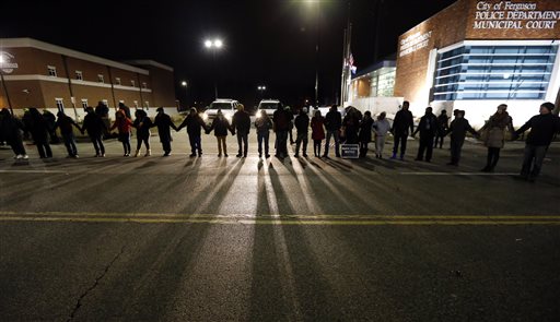 Protestors block traffic outside the Ferguson, Mo., police department, Wednesday, March 4, 2015, in Ferguson. The Justice Department on Wednesday cleared a white former Ferguson police officer in the fatal shooting of an unarmed black 18-year-old, but also issued a scathing report calling for sweeping changes in city law enforcement practices it called discriminatory and unconstitutional. (AP Photo/Charles Rex Arbogast)