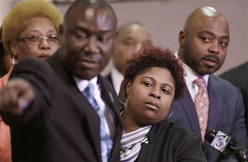Samaria Rice, center, the mother of Tamir Rice, a 12-year-old boy fatally shot by a Cleveland police officer, watches the video of Tamir's shooting during a news-conference Tuesday, March 3, 2015, in Cleveland. Attorney Benjamin Crump, left, and attorneys Walter Madison, right, watch.  Rice and her attorneys talked about the city's response to the lawsuit, a day after Cleveland Mayor Frank Jackson apologized for wording in a court document in which the city said the boy died as a result of his own actions. (AP Photo/Tony Dejak)