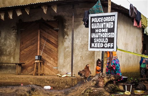 In this Wednesday, Oct. 22, 2014 file photo, a child stands near a sign advising of a quarantined home in an effort to combat the spread of the Ebola virus in Port Loko, Sierra Leone. On Tuesday, March 17, 2015, health officials said four more medical aid workers have been flown from West Africa to the United States, for monitoring for Ebola. The latest arrivals bring to 16 the number of aid workers evacuated in the last week from Sierra Leone. (AP Photo/Michael Duff, File)