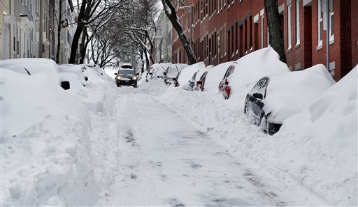 A car makes its way down a street filled with snowed-in vehicles in Boston's Charlestown section, Wednesday, Jan. 28, 2015 one day after a blizzard dumped about two feet of snow in the city. (AP Photo/Elise Amendola)