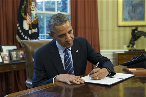 President Barack Obama signs a presidential memorandum aiming to clamp down on the private companies that service federal student debt, Tuesday, March 10, 2015, in the Oval Office of the White House in Washington. (AP Photo/ Evan Vucci)