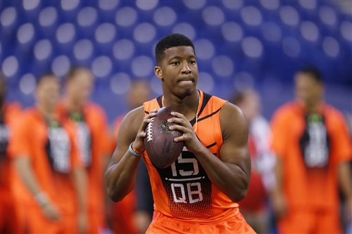 In this Feb. 21, 2015, file photo, Florida State quarterback Jameis Winston runs a drill at the NFL football scouting combine in Indianapolis. While 26 draft-eligible players have accepted invitations from the NFL to attend the proceedings later this month, Winston and Marcus Mariota are not among them. The two most recent Heisman Trophy winners and highest-profile players in this year's crop have opted to stay home with their families for the April 30-May 2 draft. (AP Photo/Julio Cortez, File)