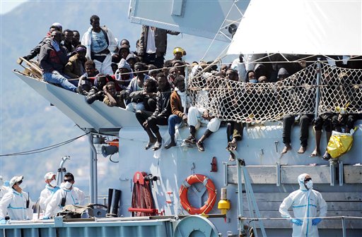 Migrants wait to disembark from the Italian Navy vessel 'Chimera' in the harbor of Salerno, Italy, Wednesday, April 22, 2015. Italy pressed the European Union on Wednesday to devise concrete, robust steps to stop the deadly tide of migrants on smugglers' boats in the Mediterranean, including setting up refugee camps in countries bordering Libya. Italian Defense Minister Roberta Pinotti also said human traffickers must be targeted with military intervention. (AP Photo/Francesco Pecoraro)