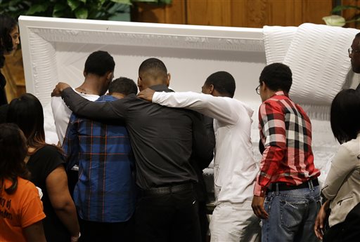 Mourners embrace as they gather in front of the casket containing the body of Freddie Gray before his funeral, Monday, April 27, 2015, at New Shiloh Baptist Church in Baltimore. Gray died from spinal injuries about a week after he was arrested and transported in a Baltimore Police Department van. (AP Photo/Patrick Semansky)