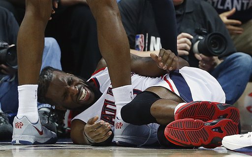 Atlanta Hawks forward DeMarre Carroll lies on the court as Atlanta Hawks forward Paul Millsap speaks after Carroll was injured against the Cleveland Cavaliers during the second half in Game 1 of the Eastern Conference finals of the NBA basketball playoffs, Wednesday, May 20, 2015, in Atlanta. (AP Photo/John Bazemore)