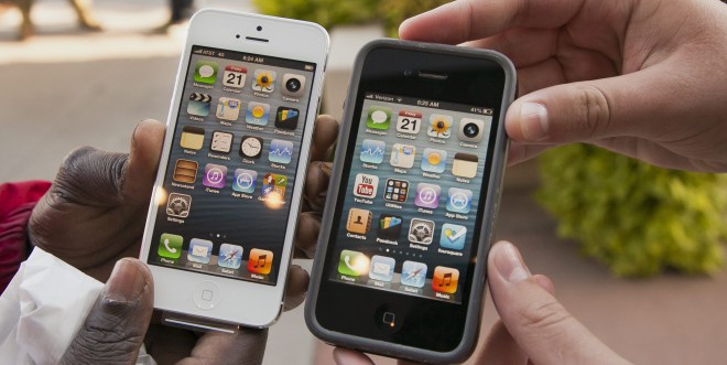 Noah Meloccaro, right, compares his older iPhone 4s to the new iPhone 5 held by Both Gatwech, outside the Apple Store in Omaha, Neb. (Nati Harnik/The Canadian Press/AP)