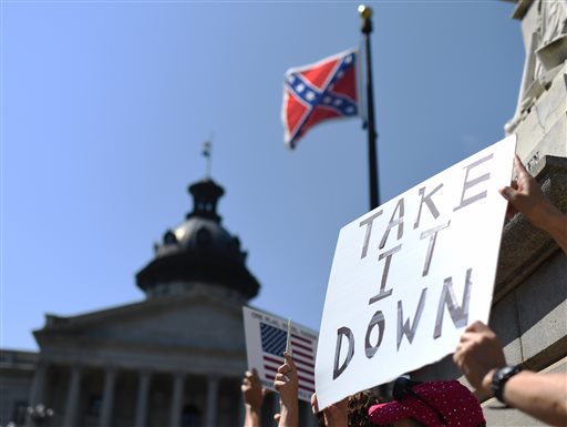 Protesters hold a sign during a rally to take down the Confederate flag at the South Carolina Statehouse, Tuesday, June 23, 2015, in Columbia, S.C. For years, South Carolina lawmakers refused to revisit the Confederate flag on Statehouse grounds, saying the law that took it off the dome was a bipartisan compromise, and renewing the debate would unnecessarily expose divisive wounds. The shooting deaths of nine people at a black church in Charleston, S.C., have reignited calls for the Confederate flag flying on the grounds of the Statehouse in Columbia to come down. (AP Photo/Rainier Ehrhardt)