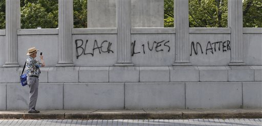 A passerby photographs the spray painted message of Black Lives Matter that was painted on a monument to former Confederate President Jefferson Davis on Monument Avenue in Richmond, Va., Thursday, June 25, 2015. The vandalism comes after a mass shooting in Charleston South Carolina has sparked a nationwide debate on the public display of Confederate imagery.  (AP Photo/Steve Helber)