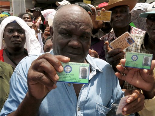 Haitian Jaquenol Martinez shows a card that proves that he has worked in the Dominican sugar cane fields since 1963, while trying to apply for a temporary resident permit, in Santo Domingo, Dominican Republic, Monday, June 15, 2015. Hundreds of Haitians are waiting in long lines throughout the Dominican Republic trying to secure legal residency as they face the threat of deportation. The government has given non-citizens until Tuesday to register under an initiative aimed at regulating the flow of migrants from neighboring Haiti. (AP Photo/Ezequiel Abiu Lopez)