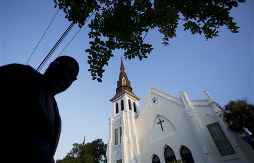 Emanuel AME Church stands in the background as a mourner visits a sidewalk memorial in memory of the shooting victims Saturday, June 20, 2015, in Charleston, S.C. (AP Photo/David Goldman)