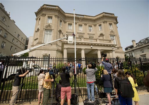 FILE - In this June 10, 2015 file photo, members of the media cover workers from Eastern Shores Flagpoles raising a flagpole at the Cuban Interest Section in Washington in preparation for re-opening of embassies in Havana and Washington. Cuba's blue, red and white-starred flag is set to fly Monday, July 20 outside the country's diplomatic mission in the United States for the first time since the countries severed ties in 1961. (AP Photo/Pablo Martinez Monsivais, File)
