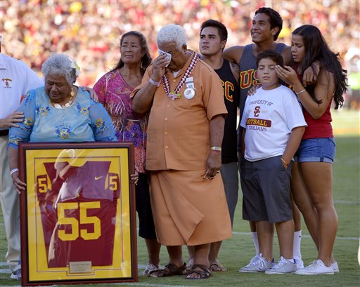 In this Sept. 1, 2012, file photo, family members of Junior Seau including his mother Luisa Seau, far left, and his father Tiaina Seau, third from left, stand during a ceremony to honor the former Southern California player during the first half of an NCAA college football game between Hawaii and Southern California in Los Angeles. The family of the late Junior Seau will not disrupt the Hall of Fame ceremonies on Aug. 8, 2015, despite their disagreement with a policy preventing live remarks during a posthumous induction. (AP Photo/Mark J. Terrill, File)