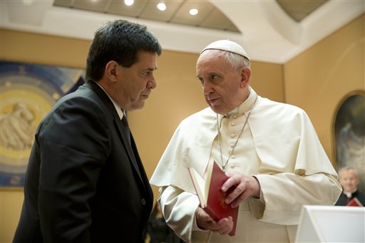 In this April 29, 2014 file photo, Pope Francis presents Paraguay's President Horacio Cartes with the book of the gospel during a private audience at the Vatican. Pope Francis is taking his "church for the poor" to three of South America's poorest and most peripheral countries, making a grueling, week-long trip that will showcase the pope at his unpredictable best: speaking his native Spanish on his home turf about issues closest to his heart. (AP Photo/Gregorio Borgia, Pool, File)