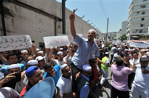 Hundreds of demonstrators of the Berber community stage a protest in front of a walled area where Algier's newspapers are headquartered in support of Berbers in the southern Ghardaia region where at least 22 people have died in ethnic unrest, in Algiers, Algeria, Wednesday, July 8, 2015. Authorities say ethnic clashes have left at least 22 people dead around Algeria's southern oasis city of Ghardaia, more than 600 kilometers (375 miles) south of Algiers, prompting the president to call an urgent security meeting. The Berbers and the Arabs in Ghardaia had for centuries lived together in harmony, but tensions started in late 2013 when a Berber shrine was vandalized. (AP Photo/Sidali Djarboub)