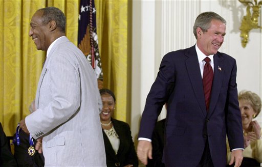 In this July 9, 2002 file photo, President George W. Bush lets out a laugh after failing to get the clasp together on Bill Cosby's Presidential Medal of Freedom, which he holds, after Bush tried to put on the entertainer, in the East Room of the White House in Washington. President Barack Obama is rejecting the idea of revoking Cosby's Presidential Medal of Freedom because of sexual misconduct allegations. Obama says there's no precedent or mechanism to take back the medal. He declined to talk about the specific allegations against Cosby because there are pending legal matters. (AP Photo/Kenneth Lambert, File)