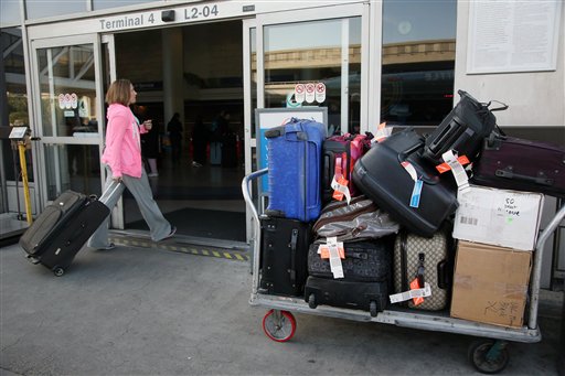 In this March 27, 2014 file photo, a baggage cart sits outside a terminal at Los Angeles International Airport in Los Angeles. A Senate committee report urges the Transportation Department to crack down on unfair or hidden airline fees for things like seat reservations, checked baggage and ticket changes or cancellations. The report is on an investigation by the Democratic staff of the Senate Commerce Committee. It says there appears to be no justification for checked bag fees other than increased profit. The report recommends that any bag fees be tied to actual costs incurred by an airline.  (AP Photo/Nick Ut, File)