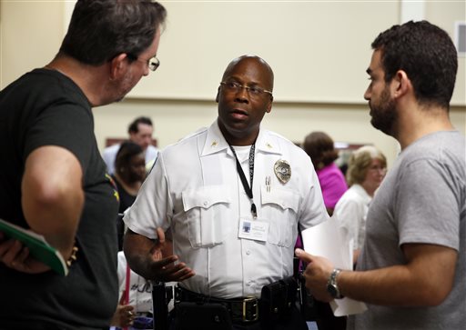 In this July 28, 2015, file photo, interim police Chief Andre Anderson, center, talks with activists John Powell, left, and Marc DeSantis at the end of a city council meeting in Ferguson, Mo. Anderson says he wants his officers engaging with the community, getting out of their cars and mingling with people in an effort to build better relations. As Ferguson protests fade, activists and the suburb are looking ahead. (AP Photo/Jeff Roberson, File)