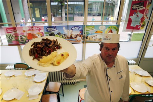 In this May 6, 2014 file photo, French chef Xavier Lebeau poses with a plate of Quenelles de Brochet (pike fish) with Green Haricot beans and Champignons de Paris (Paris mushrooms), at the Saint Pierre de Chaillot school in Paris, France. France has been grappling with how to reconcile religious beliefs with secular values when it comes to pork in school lunches, with one lawmakers solution: vegetarian meals. (AP Photo/Francois Mori, File)