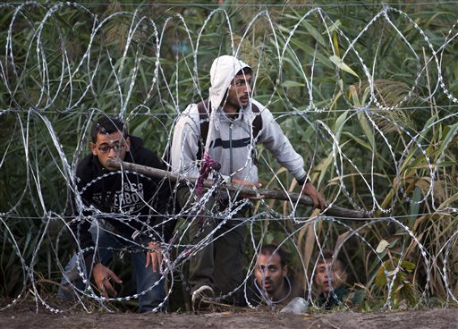 Syrian refugees get ready to enter Hungary from Serbia, on the border near Roszke, Friday, Aug. 28, 2015. Hungary deployed police reinforcements to rein in an unrelenting flow of migrants across its porous border Thursday, but refugee activists said the effort appeared futile in a nation whose migrant camps are overloaded and barely delay their journeys west into the heart of the European Union. (AP Photo/Darko Bandic)