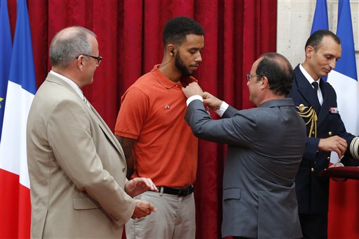 French President Francois Hollande, right, awards with the Legion of Honor Anthony Sadler, a senior at Sacramento University in California as British businessman Chris Norman, left, looks on at the Elysee Palace, Monday Aug.24, 2015 in Paris, France. Hollande  pinned the Legion of Honor medal on U.S. Airman Spencer Stone, National Guardsman Alek Skarlatos, and their years-long friend Anthony Sadler, who subdued the gunman as he moved through the train with an assault rifle strapped to his bare chest. The British businessman, Chris Norman, also jumped into the fray. (AP Photo/Michel Euler, Pool)