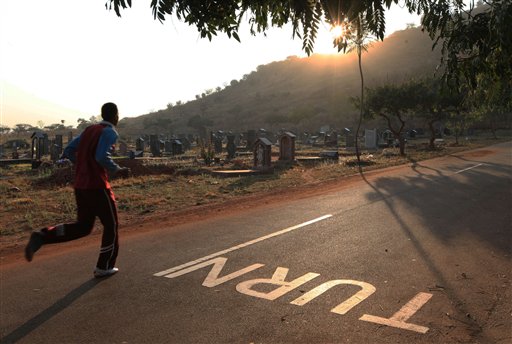 In this photo taken Saturday July 25, 2015, a jogger passes  through the Warren Hills Cemetery in Harare. Due to lack of gyms and other exercise venues in many Harare neighborhoods, the cemetery has become a workout site for many fitness enthusiasts. (AP Photo/Tsvangirayi Mukwazhi)