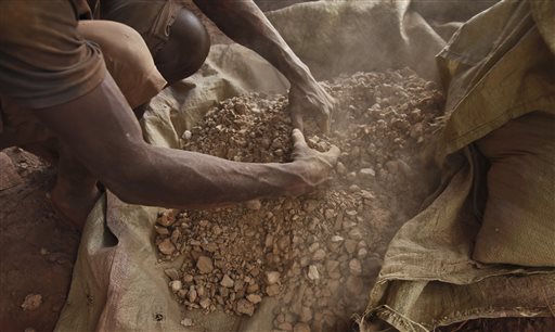 In this photo taken Wednesday, Aug. 19, 2015, a Ugandan gold miner sorts gold ore before it is loaded into a milling machine, in the Mubende district west of the capital Kampala, in Uganda. The gold rush is on in a big way in the Ugandan district of Mubende, with tens of thousands of people making their livelihood from it. (AP Photo/Stephen Wandera)