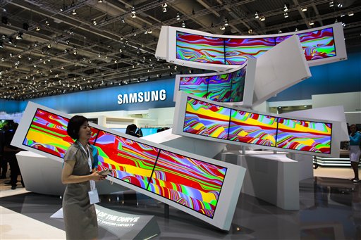 This is a Friday, Sept. 5, 2014 file photo of a woman as she passes an installation with curved screens, displayed by Samsung at the consumer electronic fair IFA in Berlin, Germany. Europes flagship gadget show, the IFA in Berlin, opens its doors to the public on Friday Sept. 4, 2015 . Almost 1,500 companies and over 250 000 people are expected to visit the event, which runs through Sept. 9. (AP Photo/Markus Schreiber)