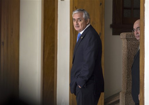 Guatemala's President Otto Perez Molina, center, leaves a press conference followed by his spokesman Jorge Ortega, in Guatemala City, Monday, Aug. 31, 2015. The head of Guatemala's congress says that lawmakers would decide on Tuesday whether to lift Perez Molina's immunity from prosecution in a corruption case, as recommended by a legislative committee. (AP Photo/Luis Soto)