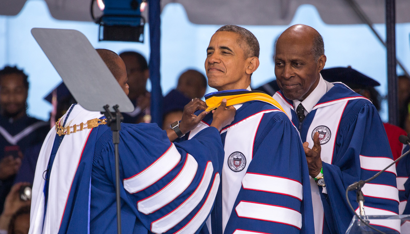 President Wayne A. I. Frederick (left) adjusts President Obama's hood as civil rights icon Vernon Jordan looks on during the 2016 Howard University Commencement ceremony on May 7, 2016 in Washington, D.C. President Obama received an honorary science doctorate for his work on the Affordable Care Act. (Cheriss May/HUNS)