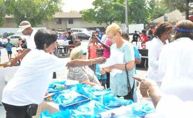 Community organizer Shirley Sharp hands out bags of books and school supplies at the Milwaukee Times table to attendees of the Northwest Funeral Home Back-to-School Book Bag Give-a-Way on Saturday, August 25, 2018