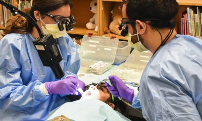 Students from Texas A&M College of Dentistry, Nida Suleman (left) and Shahriar Soroushi (right) provides a third grader free sealants in the library of Thomas Haley Elementary, in Irving. (Photo: Rachel Hawkins/North Dallas Gazette)