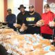 AFTER PICKING UP their hams, local veterans and their families selected desserts and the rest of the Christmas dinner trimmings as they moved through the serving line manned by Webb House volunteers including (l -r): Steve Mays, former Chicago Bear Jim Osborne, Machail Watkins, United Steelworkers Local 1014, Nate Cain, Robert Buggs and Indiana State Senator Lonnie Randolph.