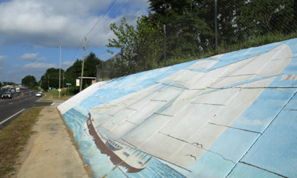 A mural of the Clotilda is painted on a retaining wall beneath the Peter Lee homeplace in Africatown on Wednesday, May 29, 2019, in Mobile, Ala. (Mike Kittrell)