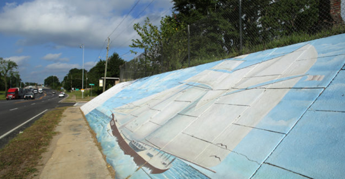 A mural of the Clotilda is painted on a retaining wall beneath the Peter Lee homeplace in Africatown on Wednesday, May 29, 2019, in Mobile, Ala. (Mike Kittrell)