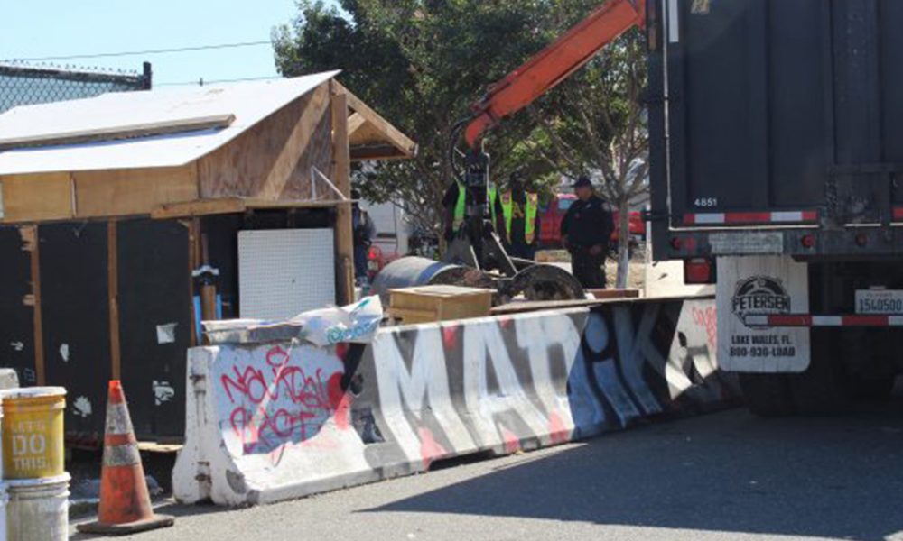Under the direction of Mayor Libby Schaaf’s city administration, and with protection from OPD, Oakland’s Department of Public Works destroys homeless resident Tommy Alexander-Ayala’s self-made home that he’d used to temporarily house friends. (Photo by: Zack Haber).