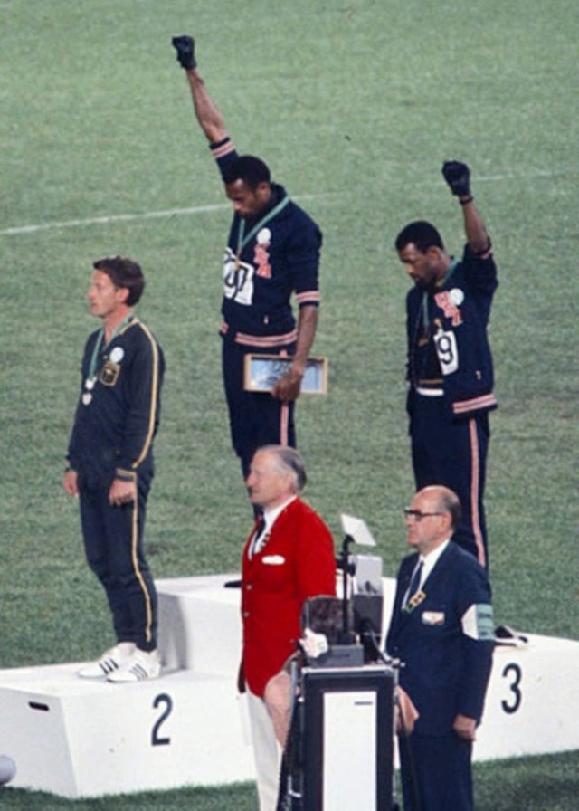 American sprinters Tommie Smith and John Carlos, along with Australian Peter Norman, during the award ceremony of the 200 m race at the Mexican Olympic games. During the awards ceremony, Smith (center) and Carlos protested against racial discrimination: they went barefoot on the podium and listened to their anthem bowing their heads and raising a fist with a black glove. Mexico City, Mexico, 1968. (Author: Angelo Cozzi (Mondadori Publishers) / Wikimedia Commons )
