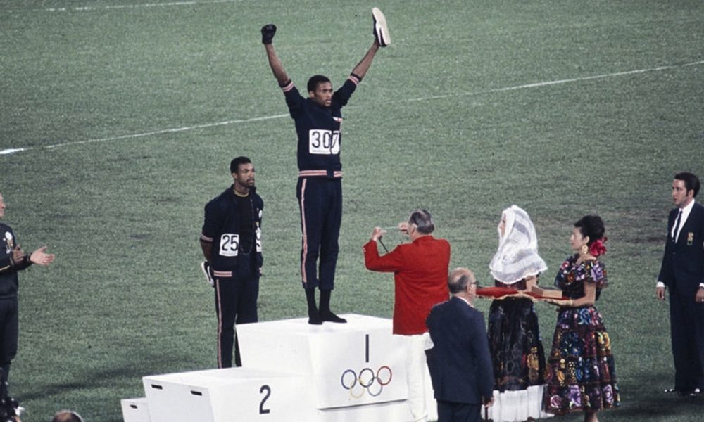 American sprinters Tommie Smith and John Carlos, along with Australian Peter Norman, during the award ceremony of the 200 m race at the Mexican Olympic games. During the awards ceremony, Smith (center) and Carlos protested against racial discrimination: they went barefoot on the podium and listened to their anthem bowing their heads and raising a fist with a black glove. Mexico City, Mexico, 1968. (Author: Angelo Cozzi (Mondadori Publishers) / Wikimedia Commons )