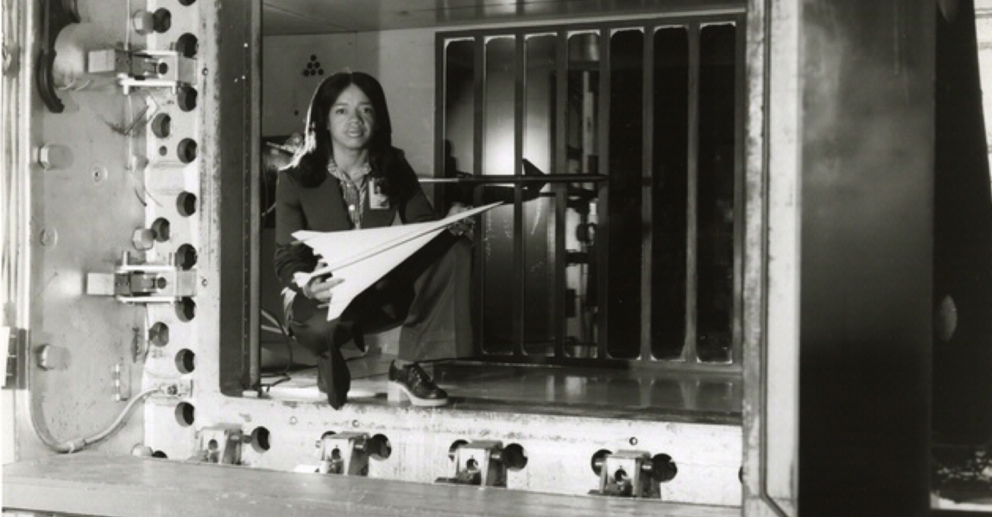 Informal portrait of NASA engineer Christine M. Darden. Darden is posed holding a wind tunnel model of a proposed aircraft while kneeling inside the test section of a wind tunnel at the NASA Langley Research Center, Hampton, Virginia. (Photo: National Aeronatics and Space Administration [NASA] / Wikimedia Commons)