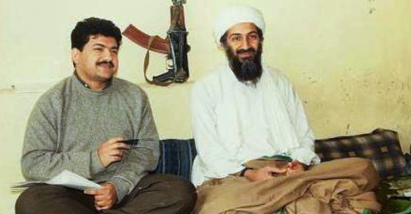 A terror mastermind named Osama bin Laden, who lived a cloak and dagger life more than 6,700 miles away in Afghanistan. (Photo: Pakistani journalist Hamid Mir interviewing Osama bin Laden, circa March 1997 – May 1998. Behind them on the wall is an AKS-74U carbine. / http://www.canadafreepress.com/ — Wikimedia Commons)