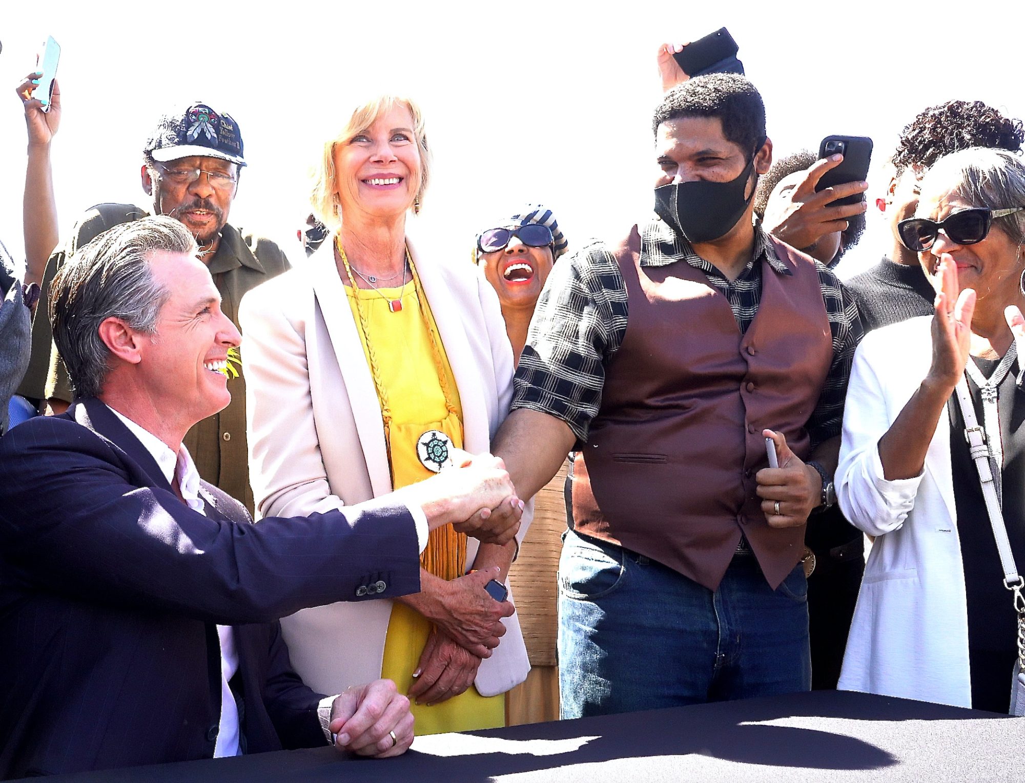 At the signing event, Newsom shakes hands with Anthony Bruce, descendant of the original owners of Bruce's Beach. Looking on are State Sen. Steven Bradford and County Supv. Janice Hahn. (E. Mesiyah McGinnis/L.A. Sentinel)