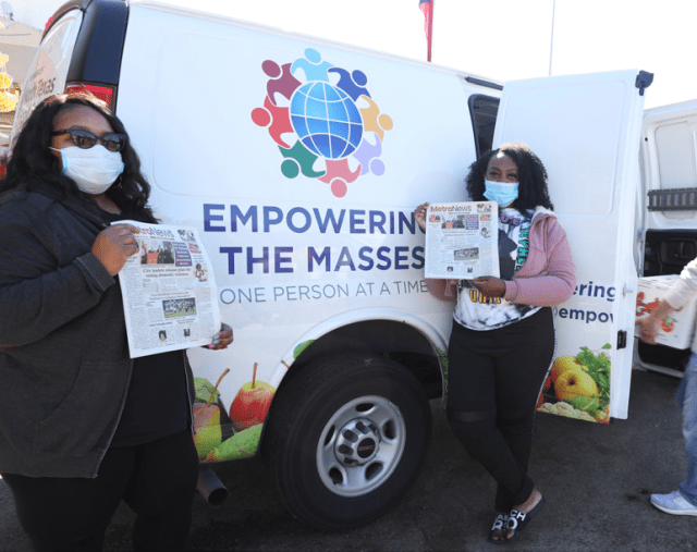 Tammy Johnson, Executive Director of Empowering the Masses, poses in front of the community van with her daughter while the last of their donations are loaded for redistribution