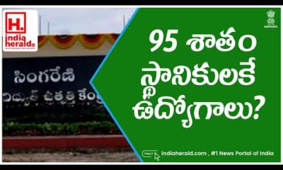 Telugu man wearing a blue shirt looking at a sign that says 95% jobs for locals